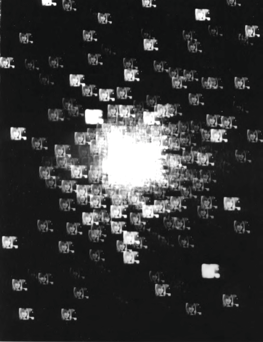 Black and white photograph: Pinhole image of a galaxy, made up of images of a woman’s head.