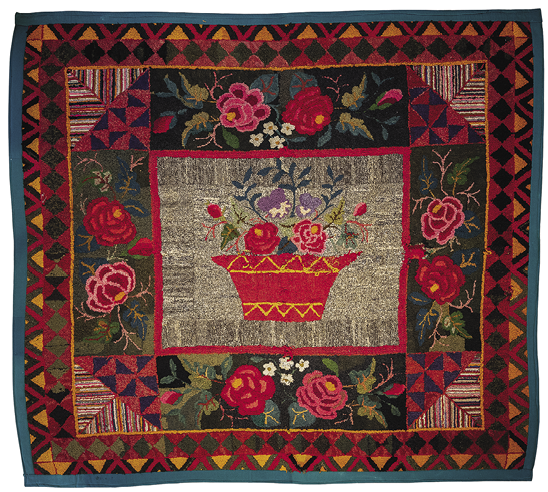 Square rug with a thick green border and then orange, red, and black geometric frame around a background of roses and smaller flowers. The center has a red outline, a grey background, and features a red pot containing red, purple, and pink flowers.