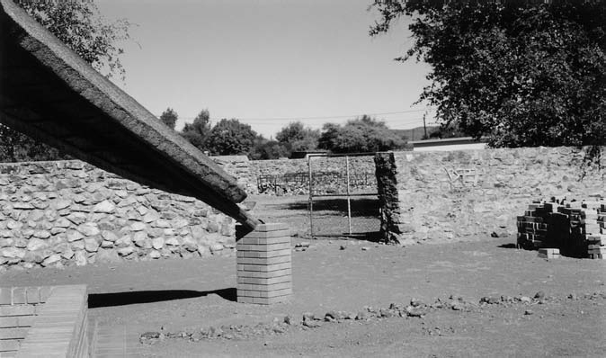 A black and white photograph of cattle kraal behind the kgotla with a boundary made with concrete.