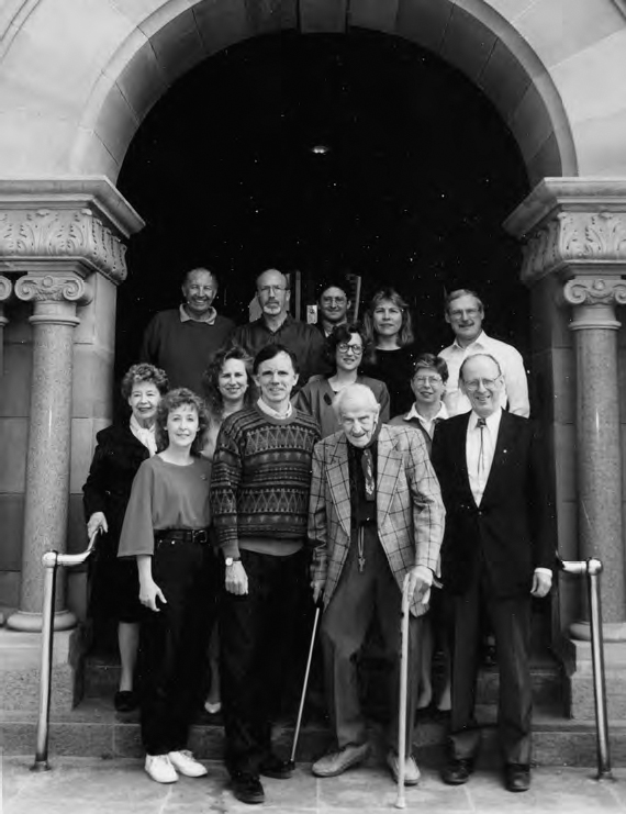 A photograph shows a group of people standing at the entrance of a traditional building.