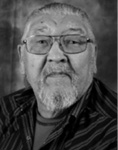 Black and white photograph: Portrait of a man wearing glasses and a striped collared shirt. 