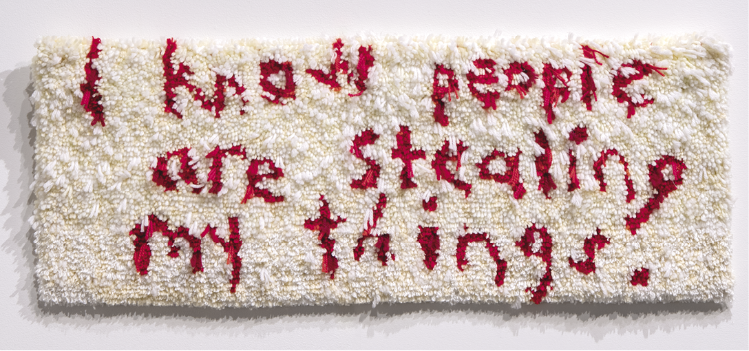 Photo: white rug with red lettering in the tufts reading, “I know people are stealing my things.”