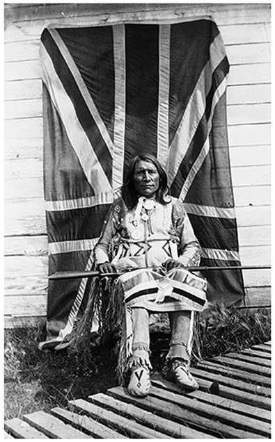 Moses Bearspaw sits in front of the Canadian flag.