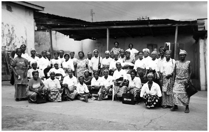 A black and white group photograph of nearly fifty Upper Manya Krobo Queenmothers, gathered in the open. 