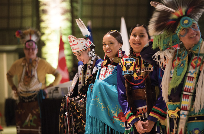 Colour Photograph: Dancers in colourful traditional regalia at the Launch event for the Indigenous Strategy.