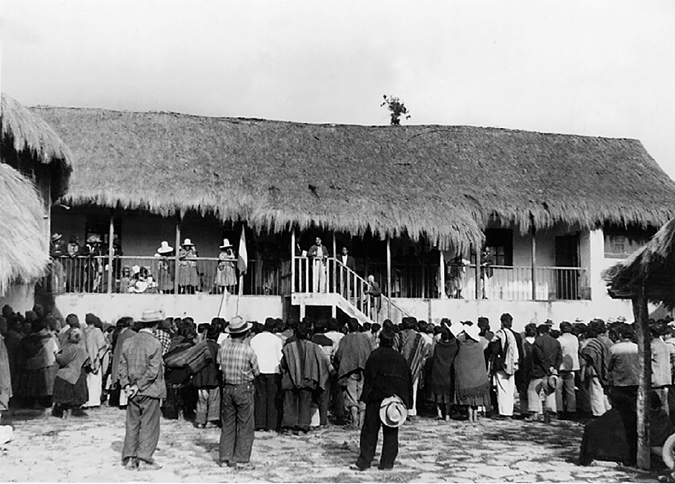 A peasant union leader address a crowd of rural workers from the balcony of the manor house of a hacienda.