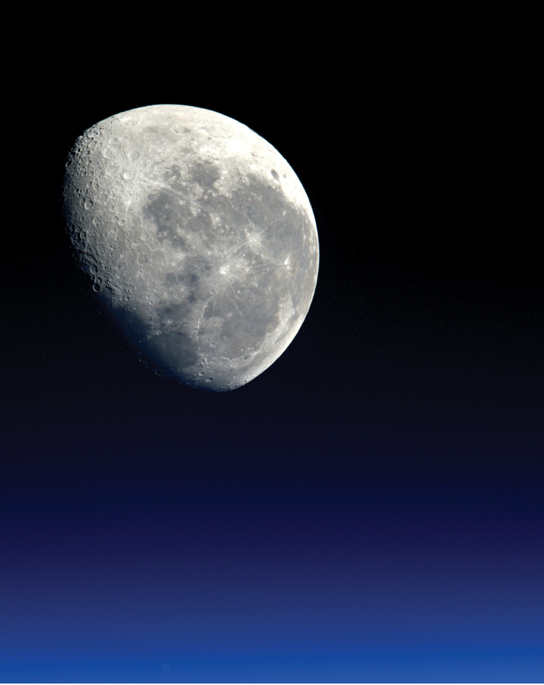 Colour photograph: The moon on a dark blue background.