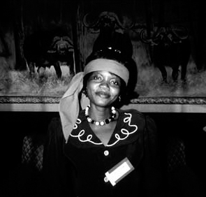 A black and white photograph of Paramount Chief Chamba of Malawi wearing a scarf over her forehead and a necklace of pearls.