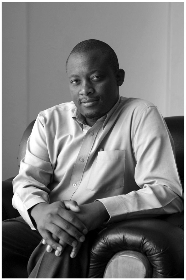 A black and white photograph of Mister Sibongiseni Mkhize, South Africa, sitting on a couch.
