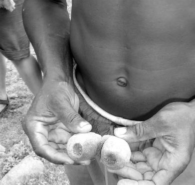 A man holds two pear-shaped conjoined objects, each having a hole in them.