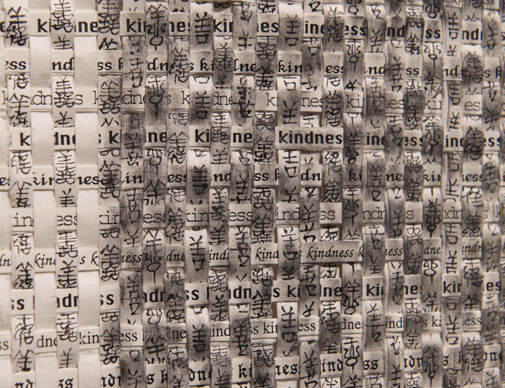 Photo: detail of the previous image showing the word “kindness” in English and a variety of other, non-Latin language on the woven strips.