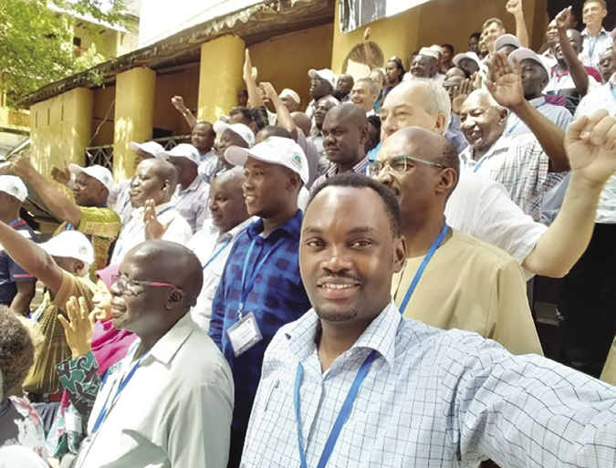Colour photograph: Photo of dozens of people at an outdoor meeting with their fists in the air.