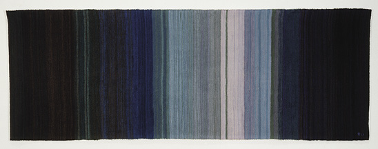 Photo: a mostly dark blue, horizontal piece that slowly morphs to lighter blue then white then back to lighter blue and dark blue.