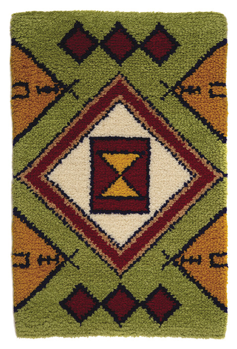 Green portrait rectangle rug with burgundy diamonds along the top and bottom middle, four orange triangles peaking in from the sides, and a large white diamond in the center outlined in black, pink, burgundy, and black with a burgundy middle. There is a yellow triangle hourglass in the very center.