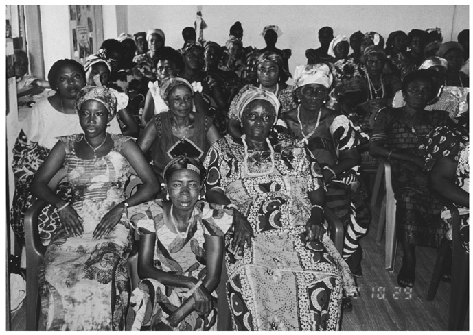 A black and white group photograph of several Queenmothers of the Manya Krobo Queenmothers Association, gathered in a room.