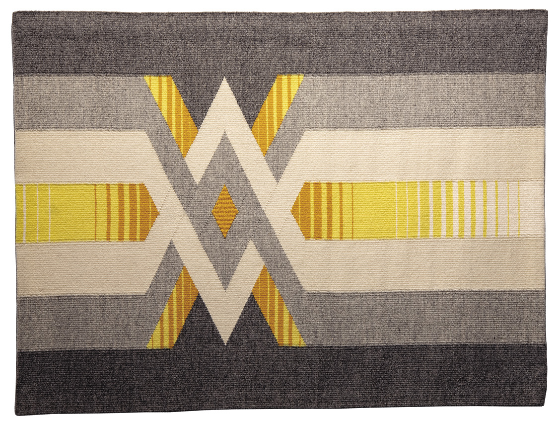 Photo: grey flag-shaped mat with horizontal lines in lighter grey, off-white, yellow, and orange intersecting in a W shape on the left-middle of the piece.