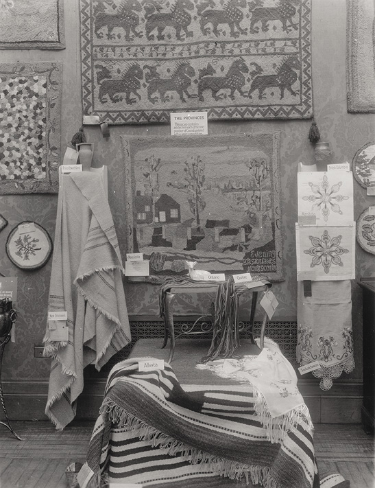 Photo noir et blanc d’un étalage de textiles divers - couvertures, pièces murales, nappes et anneaux de broderie. 