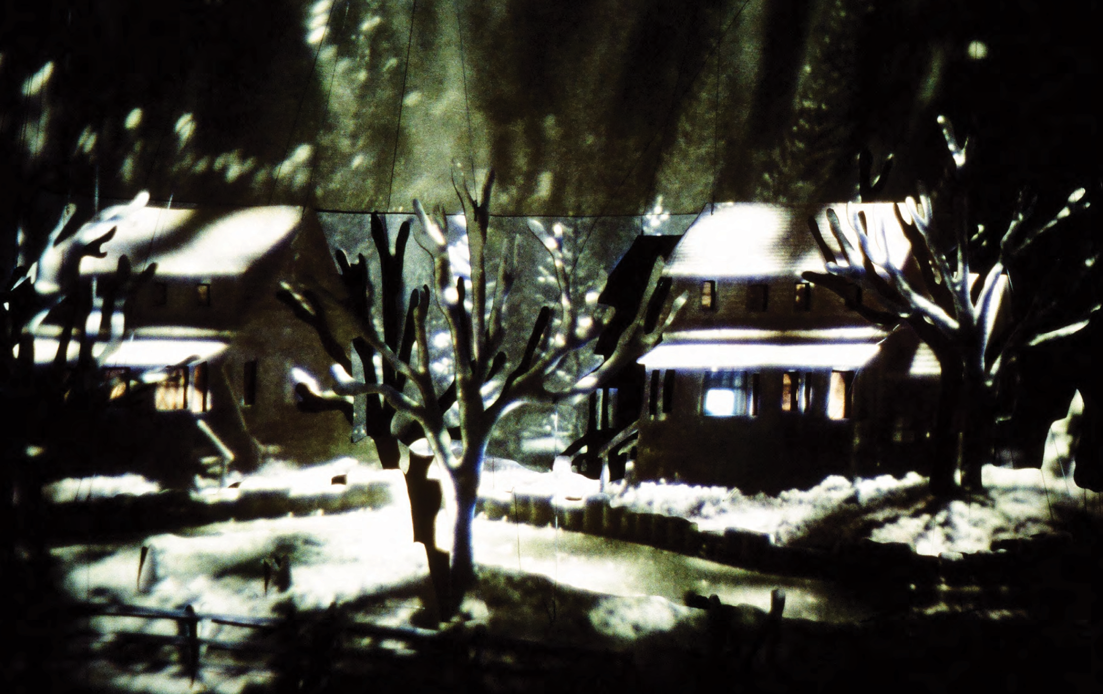 Colour photograph: A diorama with projections; an outdoor scene of snow covered houses and trees, with the bottom of a vast spaceship above.