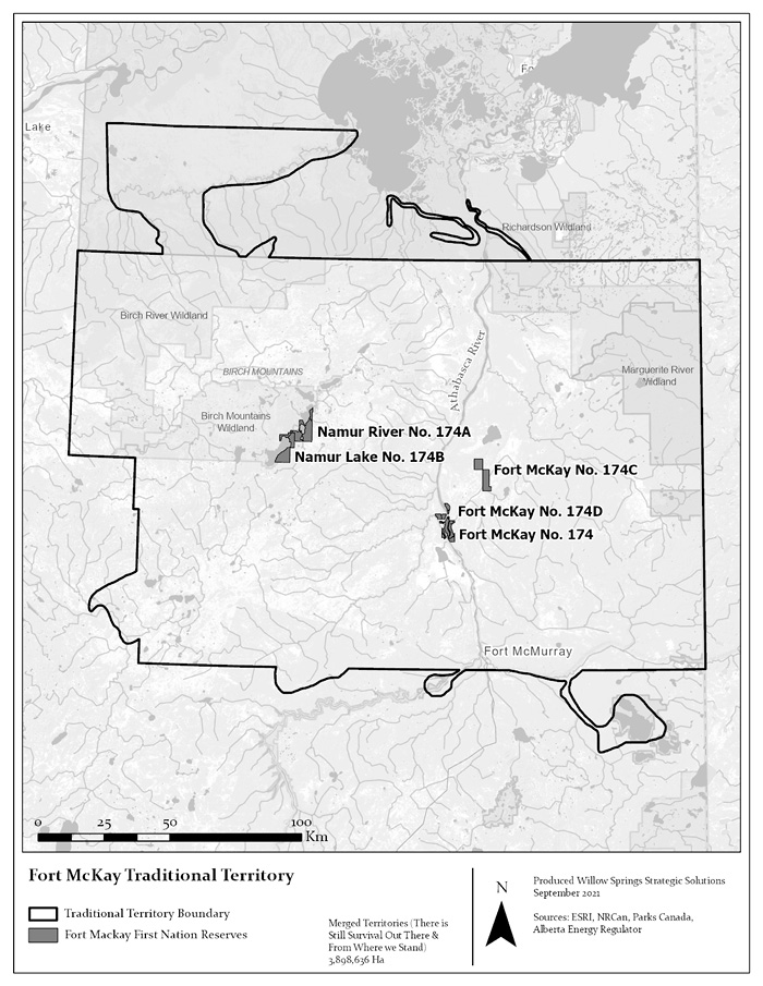 The image is a black and white map depicting the Fort McKay Traditional Territory, which is outlined with a prominent black line. The territory covers a large area in northern Alberta, Canada, shown in the context of a larger geographic region with faint topographical features and water bodies. The boundary line extends east from Fort McKay to the Saskatchewan Border, follows the border north to Richardson Wildland and west to Birch River Wildland. Within the territory, specific Fort McKay First Nation Reserves (Namur River No. 174A, Namur Lake No. 174B, Fort McKay No. 174C, Fort McKay No. 174D, and Fort McKay No. 174) are highlighted in a darker gray hue. Notable geographic features within and surrounding the area include the Birch Mountains, Athabasca River, and several wildland areas. The map includes a scale bar showing distances in kilometers and a north arrow for orientation. 