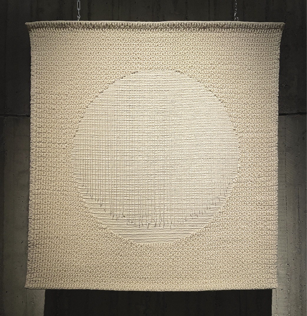 Photo: entirely beige hanging with woven threads surround a large circle with loose threads hanging down.