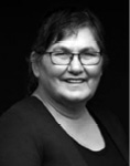 Black and white photograph: Portrait of a woman wearing glasses and scooped neck shirt with a light cardigan.