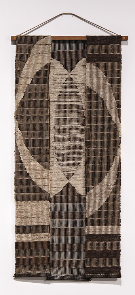 Photo: wall hanging in three panels, in brown and tan, illustrating an oblong thing with a void middle.