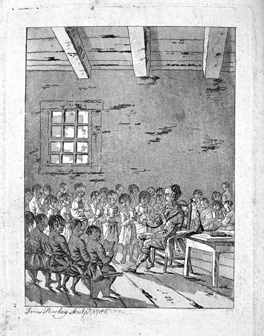 Black and white photograph of a book page: Drawing of a group of approximately thirty young Indigenous children in a classroom in the 1700s, seated on benches or standing reading. A teacher sits near the middle of the image, beside a desk. It is an older building with large rafters that looks rustic.
