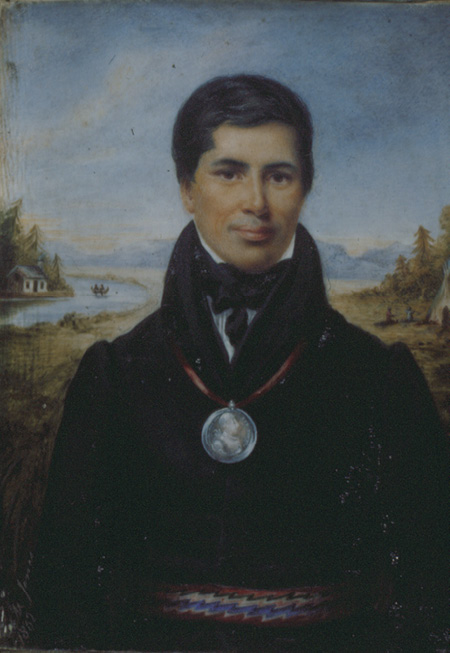 Colour painting. Portrait of an Indigenous man with short black hair and a friendly expression He is standing in a field, with a dwelling and river behind him. He is wearing a black coat and cravat, with a large silver medal on a red ribbon around his neck, and a colourful sash at his waist.
