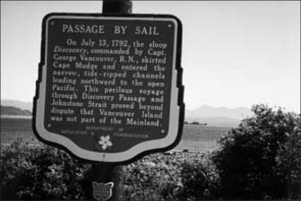 A plaque is fixed on a pole located in a field.