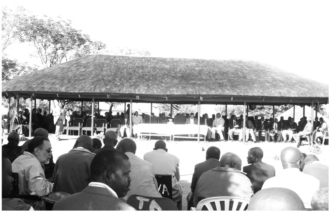 A black and white photograph of Kgotla at Mochudi, where several people are sitting under two separate canopies, with open space between them.