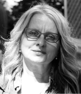 Black and white photograph: Portrait of a woman with long blond hair and glasses. She is looking at the camera with a serious expression.