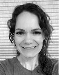 Black and white photograph: Portrait of a woman smiling and wearing a t-shirt.