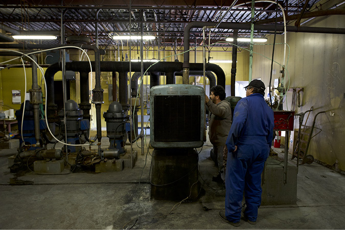 A pumphouse of pipes and equipment to provide hydro and water to residents and commercial interests in Uranium City is tended to by two skilled workers.