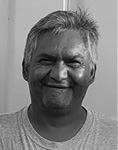 Black and white photograph: Photograph of a man in a t-shirt smiling with the sun on his face.