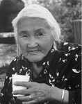 Black and white photograph: Photograph of a woman outside wearing a patterned shirt, bracelet, and holding a coffee cup.