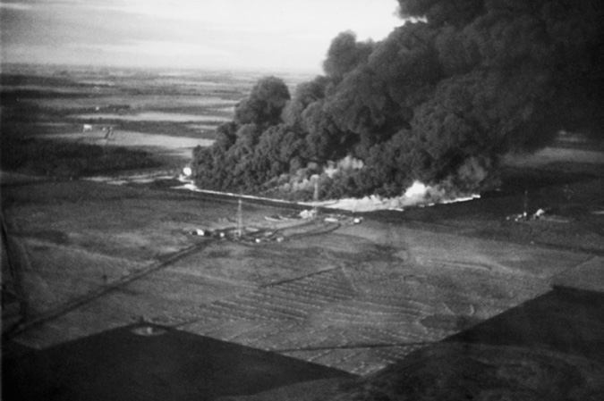 The photo is an aerial view of the fire at Atlantic #3 site in the Leduc field, which was one of the longest lasting “wild wells” in Canadian history that was eventually ended by a team headed by Tip Moroney of Jersey Standard and Imperial Oil.