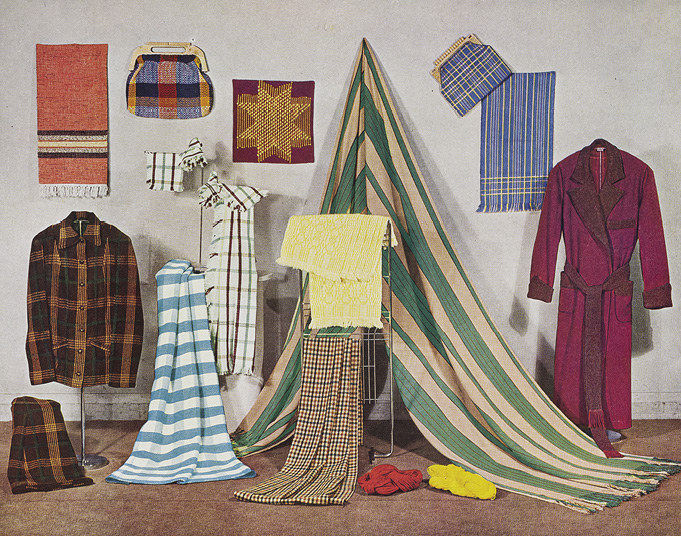 Photo : une variété de textiles de la maison disposés pour être exposés, notamment une chemise à carreaux, une serviette à rayures bleues, un sac à main bleu et orange, une poignée et un tablier, une longue couverture à rayures vertes et feu, entre autres. 