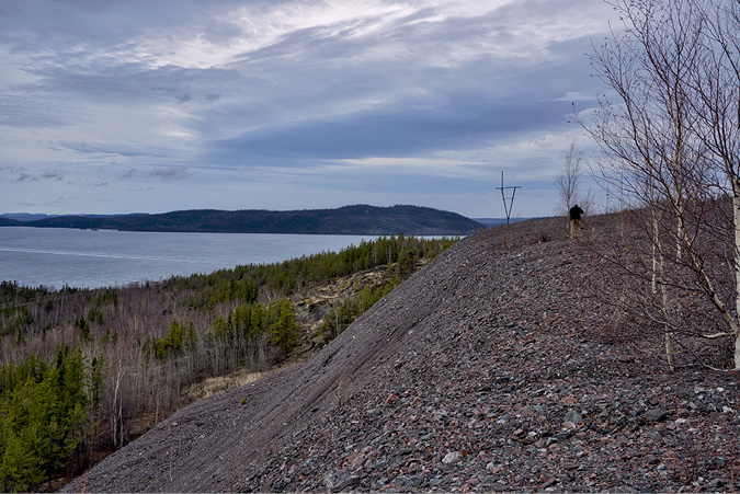 A rocky trail looks down to the Fookes Lake, under which hidden tailings of mining waste are buried. The simple lines, water and trees cover well and the scene is quiet.