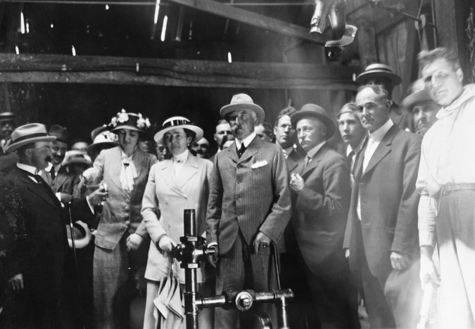 Figure 7-3 “Duke and Duchess of Connaught at Dingman number 1 well.” Black and white photograph. In the center of the photograph is the first member of the royal family to be Governor General of Canada, Prince Arthur, the Duke of Connaught, his wife Princess Louise Margerat Alecandrea Vicotria Agnes of Prussia, the Duchess of Connaught, and their daughter, Princess Patricia during their visit to Calgary and oil field at Turner Valley on July 28, 1914. Archibald Dingman, the managing partner of Calgary Petroleum Products, and Martin Hovis, one of the drillers stand next to the Duke. Meanwhile, Calgary alderman and well-known civic booster T.A.P. (“Tappy”) Frost stand beside Princess Patricia just before consuming a small glass of crude taken directly from the well.