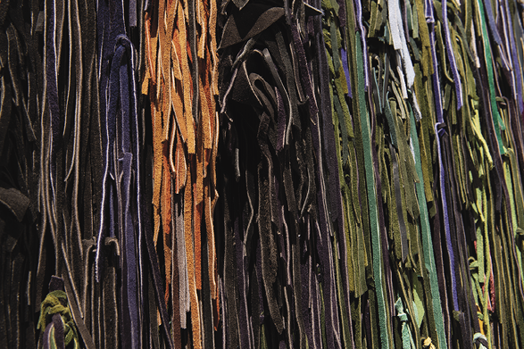 Photo: detail from previous images showing brown, blue, orange, black, green blue strips of material.