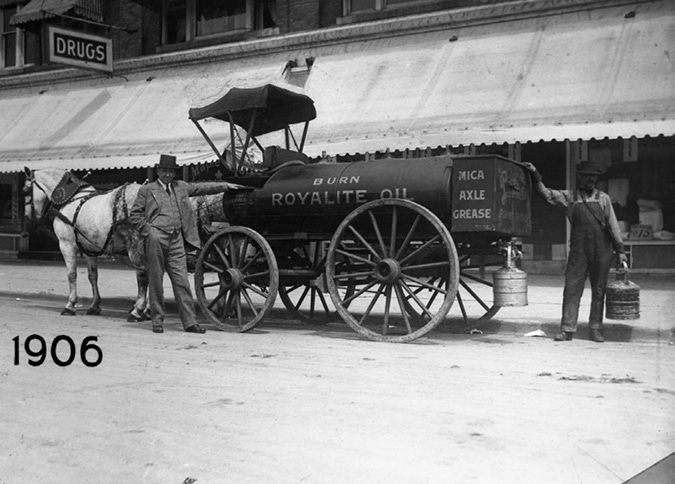 This photo shows a horse-drawn oil tank wagon in front of a drug store, with a top-hatted man next to the horse and a man in overalls carrying an oil can at the back of the wagon. Royalite was the brand name for Imperial Oil products sold in Toronto at this time.
