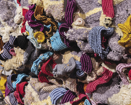 Photo: detail of the jumble of colourful cloth highlighting blue, red, purple, and gold ribbons.