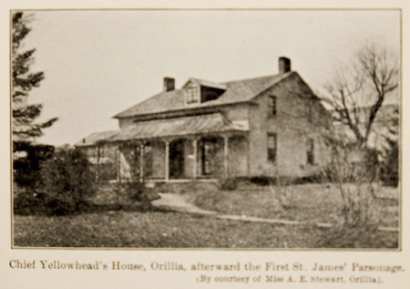 Black and white historical photograph. A large, possibly clapboard, house, with a wide verandah, a gabled roof, two chimneys, and four windows on the right side. A path leads through a garden to the house. The garden has a variety of trees and bushes, without leaves. There is a typed caption beneath the photograph.