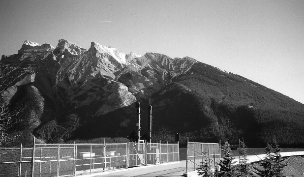 The dam at the Lake Minnewanka. The mountains in the background are partially snow-covered.
