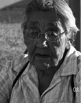 Black and white photograph: Photograph of a woman wearing glasses and a collared shirt outside on a sunny day.