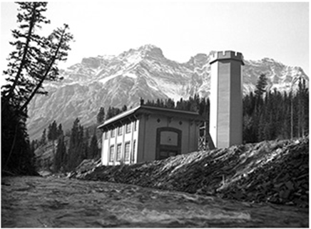 A power station building. Snow capped mountains are in the background.